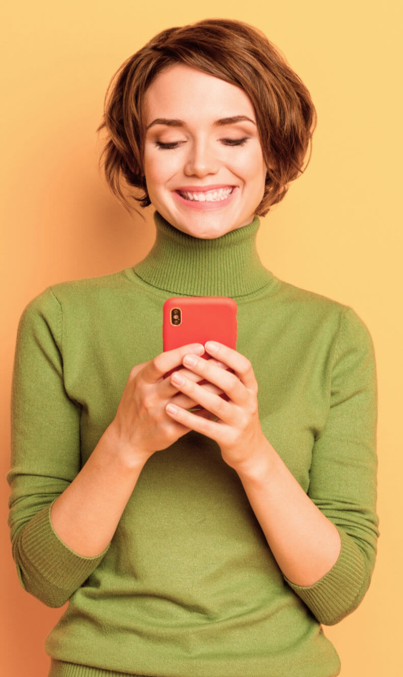 Young woman smiling and looking at her phone
